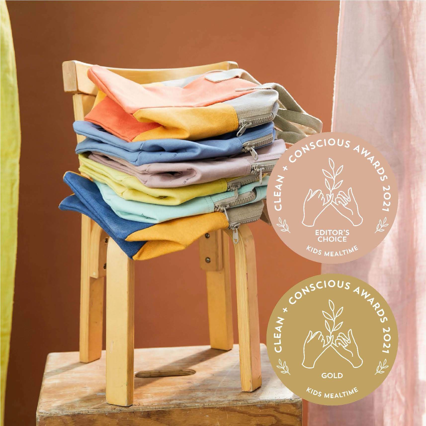 a chair with colorful Cotton sustainable lunch bags and reusable snack bags made by fluf with the logo of the CLEAN + CONSCIOUS AWARDS 2021. Gold one and the editor's choice