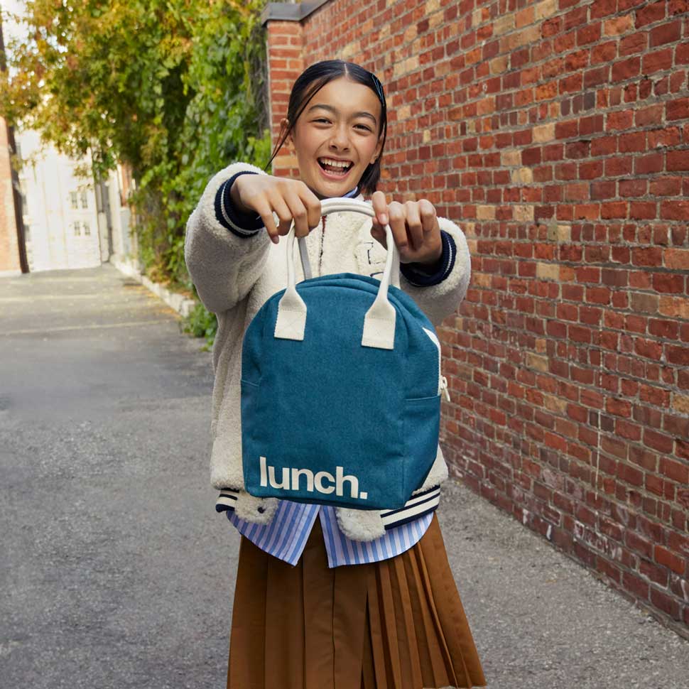 Teenager girl smiling and holding  Cypress green lunch bag by fluf