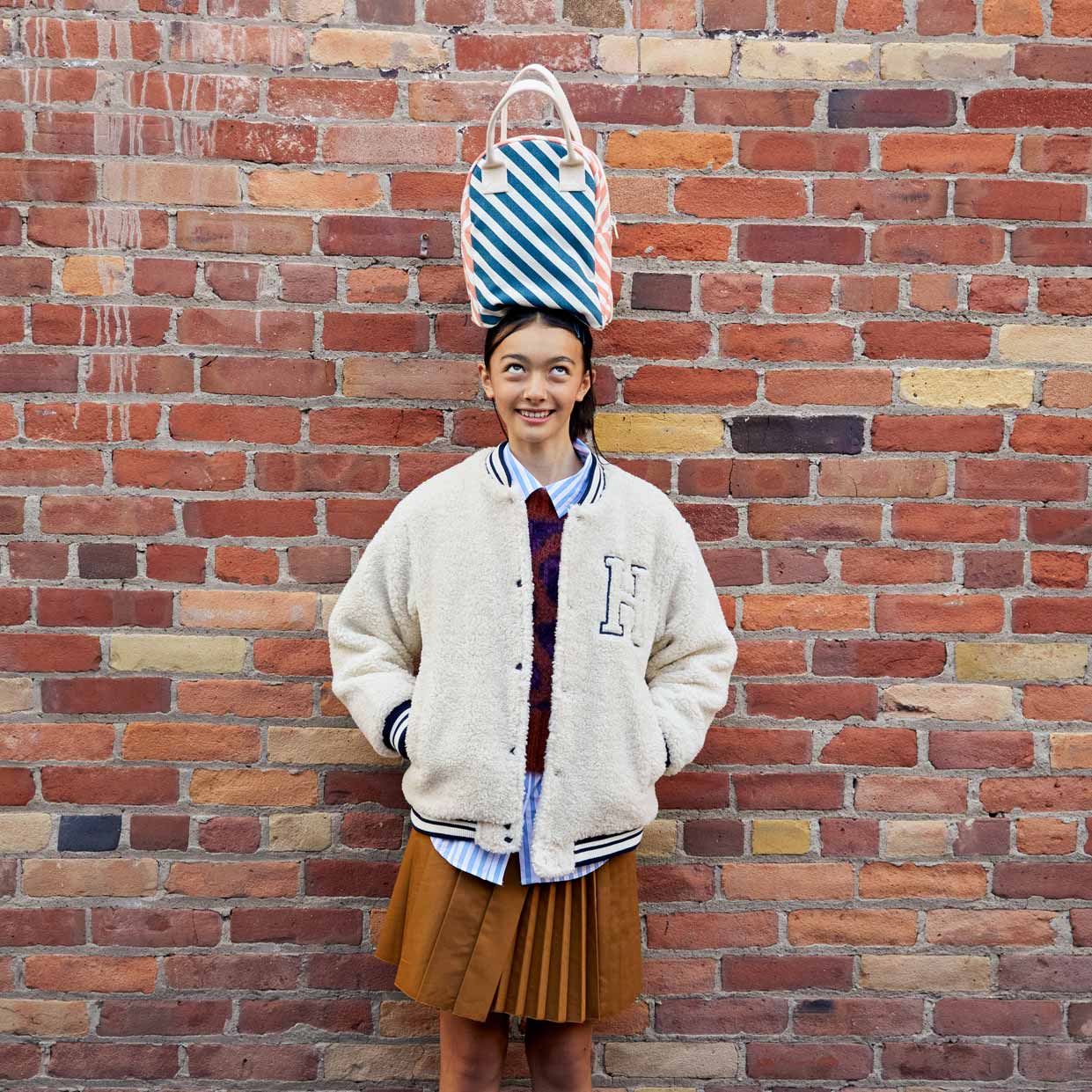 Lunch bags for teenagers presented by a teenager holding Fluf organic zipper lunch bag with strip on her head