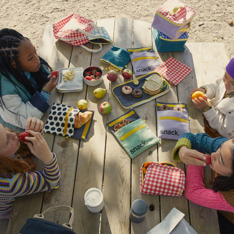 kids eating from Reusable and machine washable black polka dot snack bag in a sandwich size, with black 'snack' design. Part of the Fluf Lunch collection 