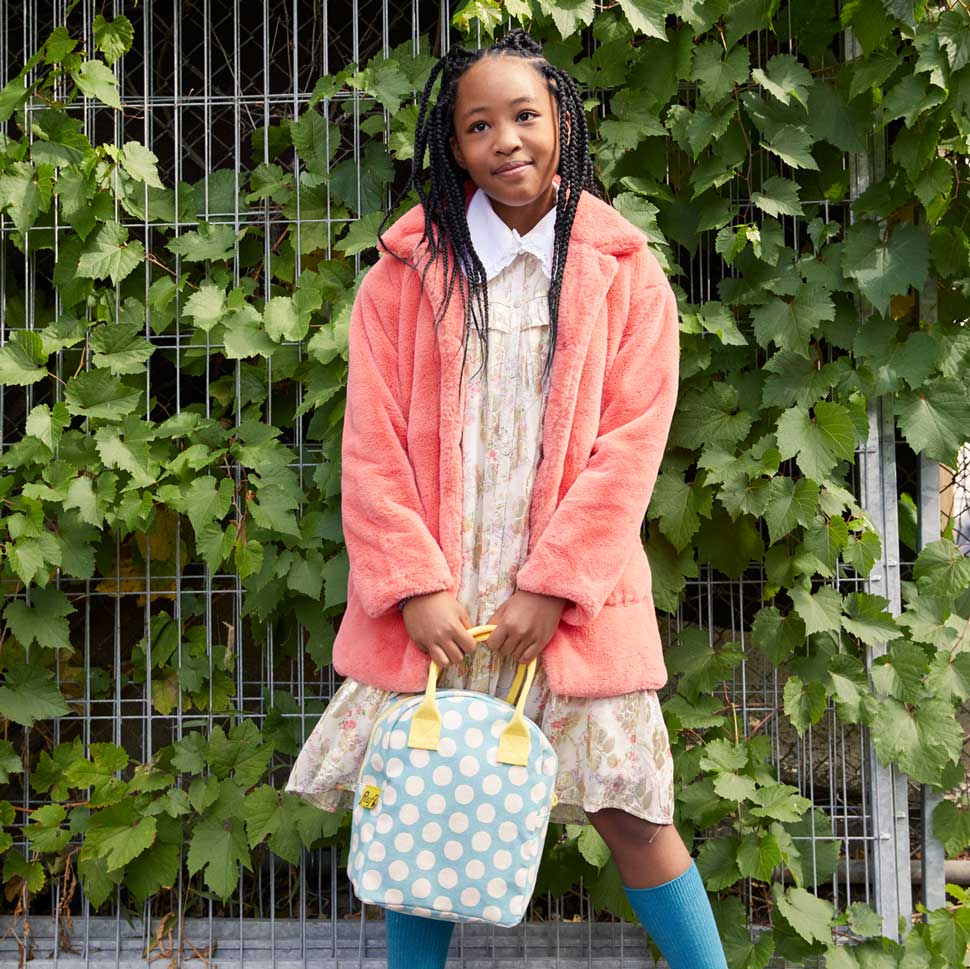 a girl holding polka dot lunch bag for school