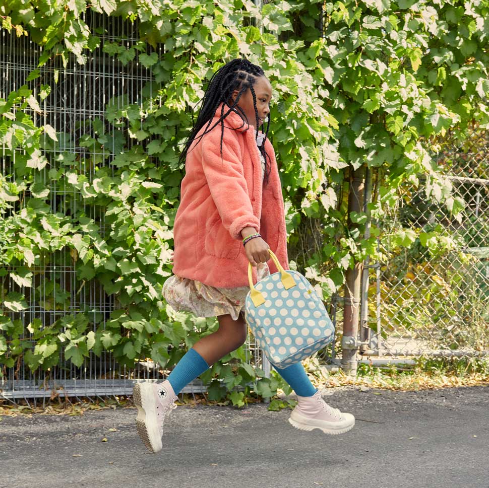 a girl jumping with zipper lunch bag in her hand 