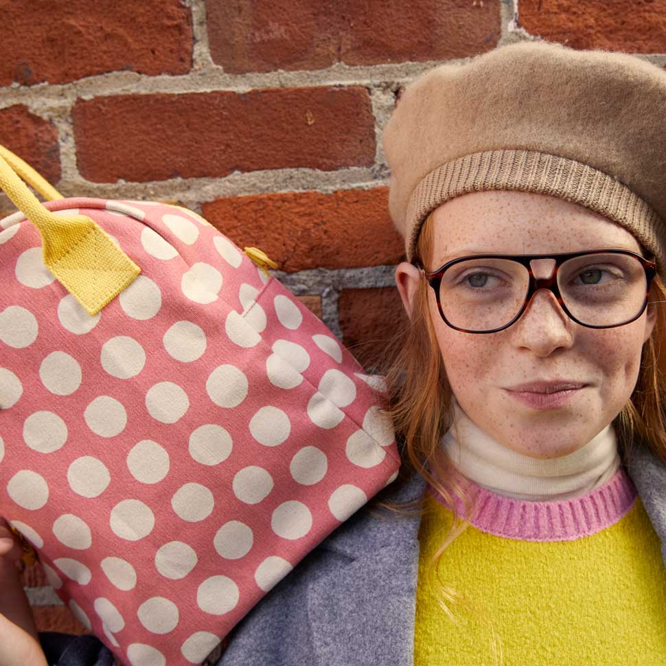 a red hair girl holding pink polka dot lunch bag