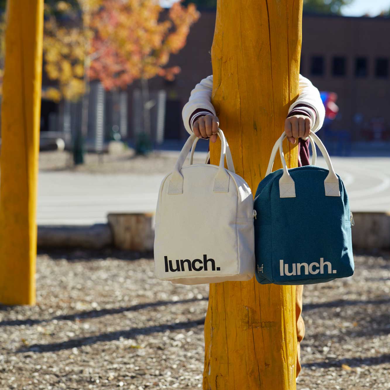 a KID holding 2 'lunch' lunch bags 